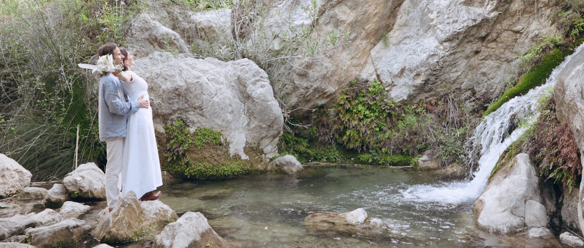 Couple sharing a personal moment amidst the magic of a waterfall during their elopement.