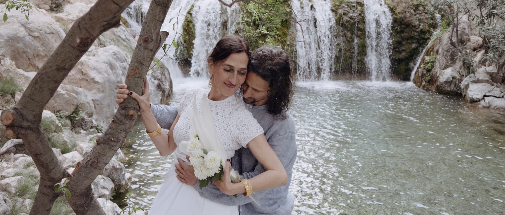 Intimate moment between couple near cascading small waterfalls during their waterfall elopement.