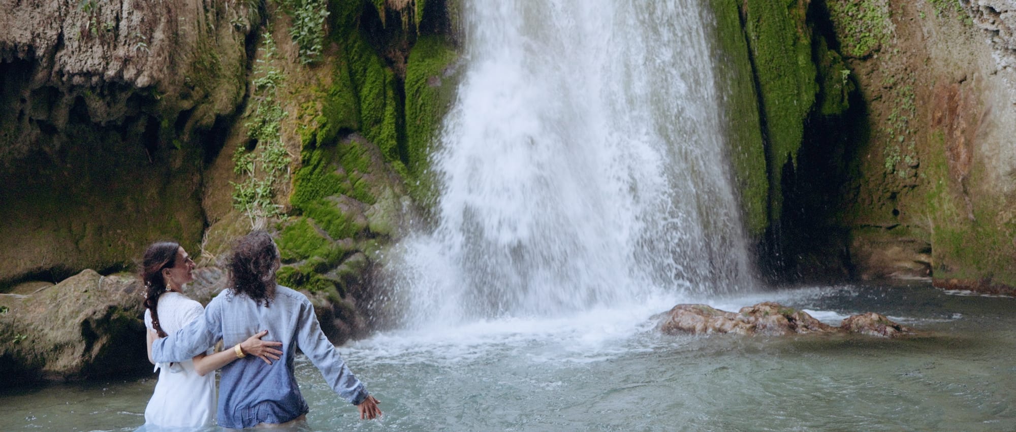 Couple gazing in awe at the powerful waterfall they discovered during their elopement adventure