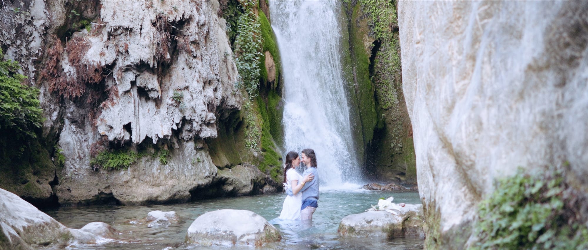 Couple embracing in front of a majestic waterfall during their waterfall elopement.